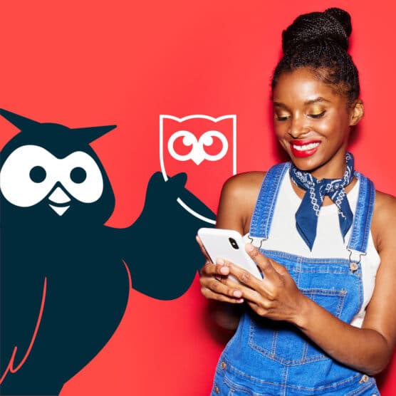 Hootsuite的吉祥物Owly站在一位正在玩手机的女士旁边